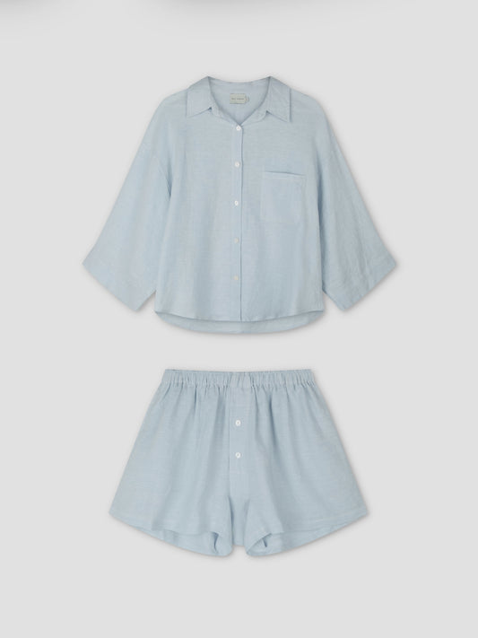 The 03 Set - Soft Blue by Deiji Studios features an oversized light blue linen shirt with a chest pocket and matching boxer-style shorts with front buttons, shown on a plain white background.