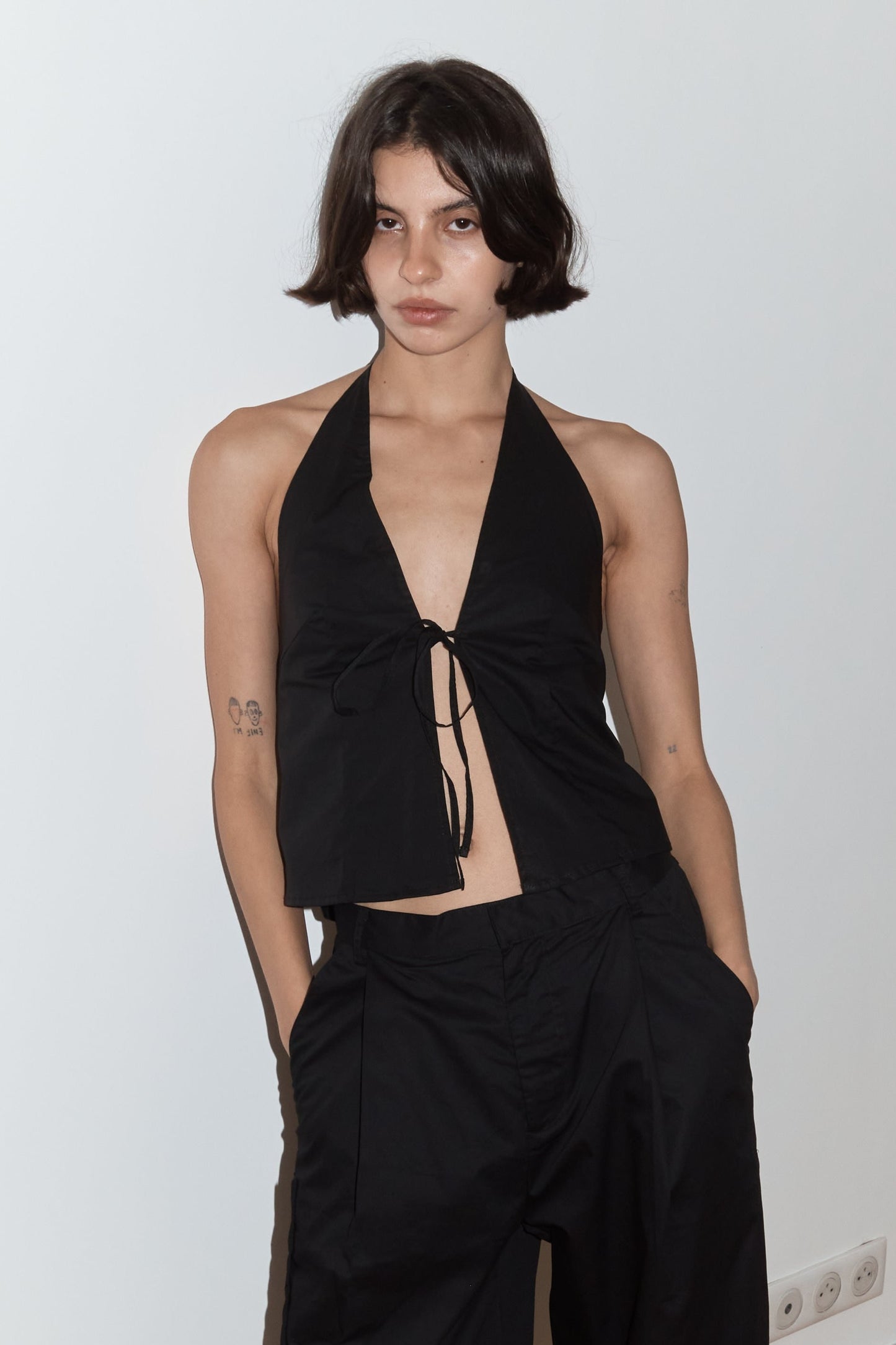 female model wears the open halter top top by Deiji Studios in black
top features open front with centre bust tie, halterneck tie and v neckline, bust seams for subtle shaping and shirred back
made from 100% GOTS certified organic cotton poplin
paired with a black cotton trouser
