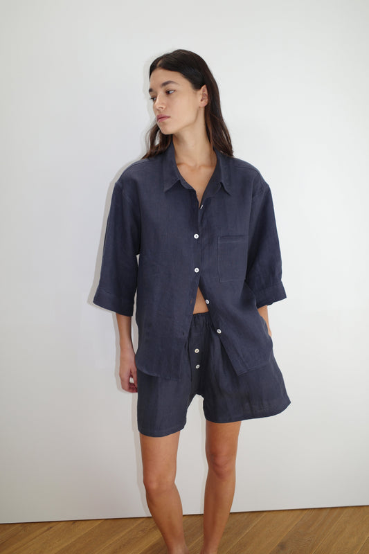 female model wears the 03 set by Deiji Studios in ink
features an oversized box fit linen shirt with wide arms and a front pocket designed to sit mid rise, the loose fitting boxer style shorts have a faux button down fly and an elastic waist for extra comfort
made from 100% GOTS certified organic, OEKO-TEX 100 certified and EU certified stone washed french linen