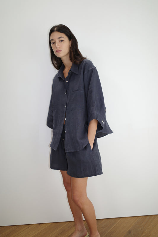 female model wears the 03 set by Deiji Studios in ink
features an oversized box fit linen shirt with wide arms and a front pocket designed to sit mid rise, the loose fitting boxer style shorts have a faux button down fly and an elastic waist for extra comfort
made from 100% GOTS certified organic, OEKO-TEX 100 certified and EU certified stone washed french linen