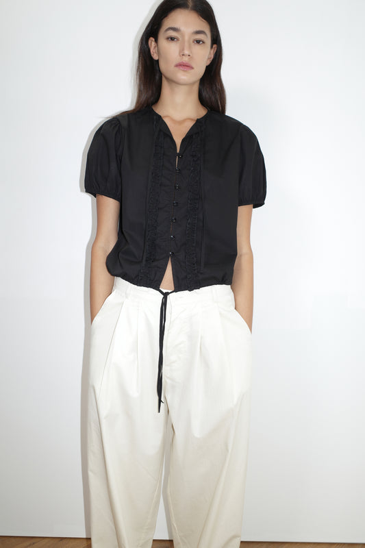 female model wears the double frill top by Deiji Studios in black
elevated everyday top features a flattering v neckline with button down front, fixed ruffle details, soft bloussant sleeve and gathered elastic cuffs
made from 100% GOTS certified organic cotton poplin
paired with a white cotton trouser