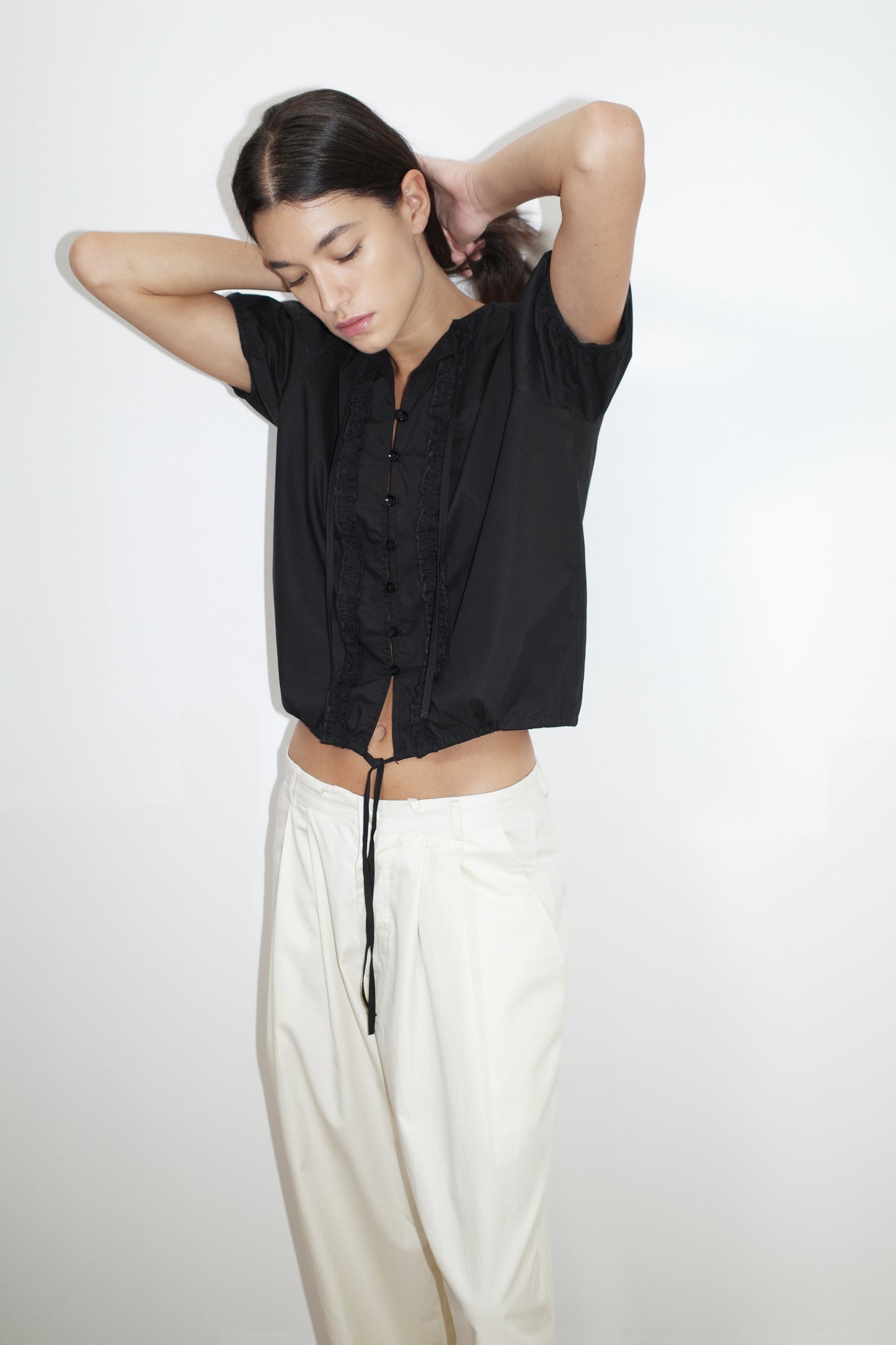 female model wears the double frill top by Deiji Studios in black
elevated everyday top features a flattering v neckline with button down front, fixed ruffle details, soft bloussant sleeve and gathered elastic cuffs
made from 100% GOTS certified organic cotton poplin
paired with a white cotton trouser