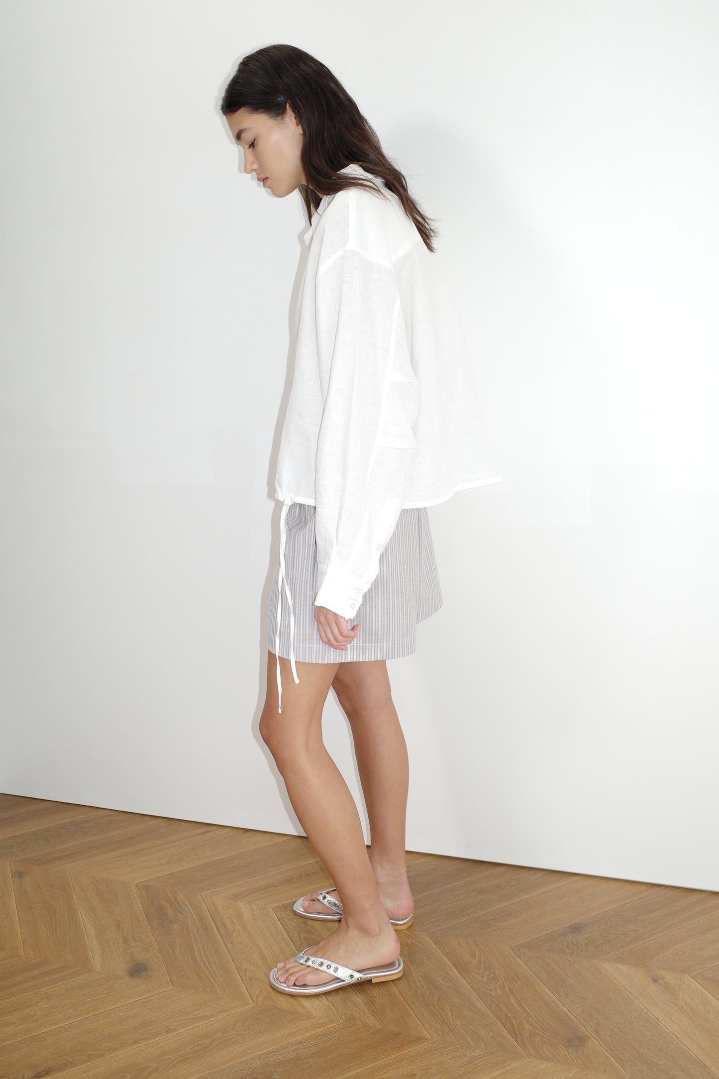 female model wears the hem shirt by Deiji Studios in white
a classic button up style shirt featuring a drawcord tie channel at bottom hem, dropped back yoke and dropped shoulder for a relaxed fit
made from 100% OEKO-TEX 100 certified and EU certified stone washed french linen
paired with boxer short in seas stripe