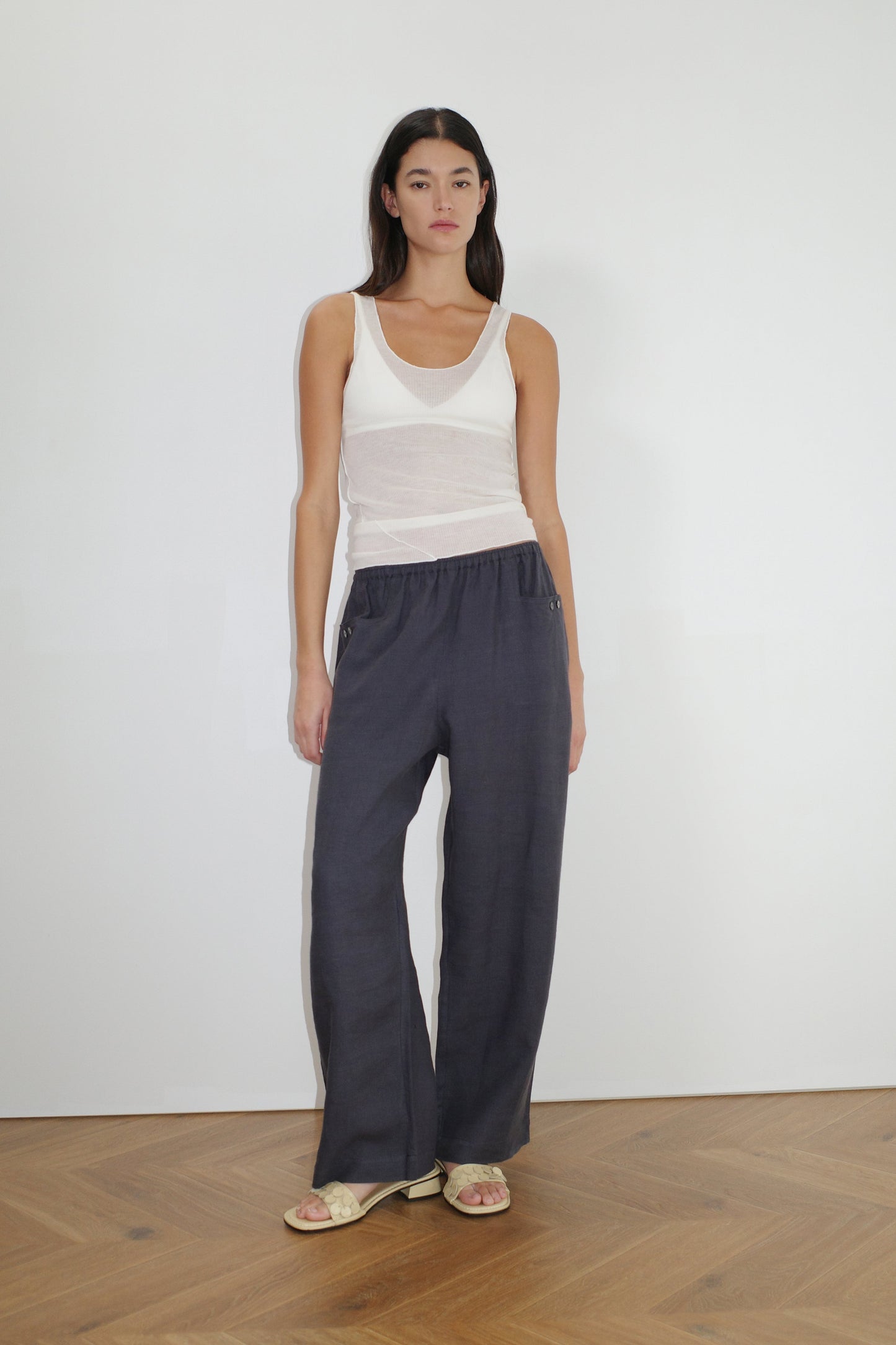 female model wears the linen square pocket pant by Deiji Studios in ink
an ankle length, straight leg pant features a soft minimal elastic waist with front seam pockets and button detail
made from 100% GOTS certified organic, OEKO-TEX 100 certified and EU certified stone washed french linen
paired with a white knit tank
