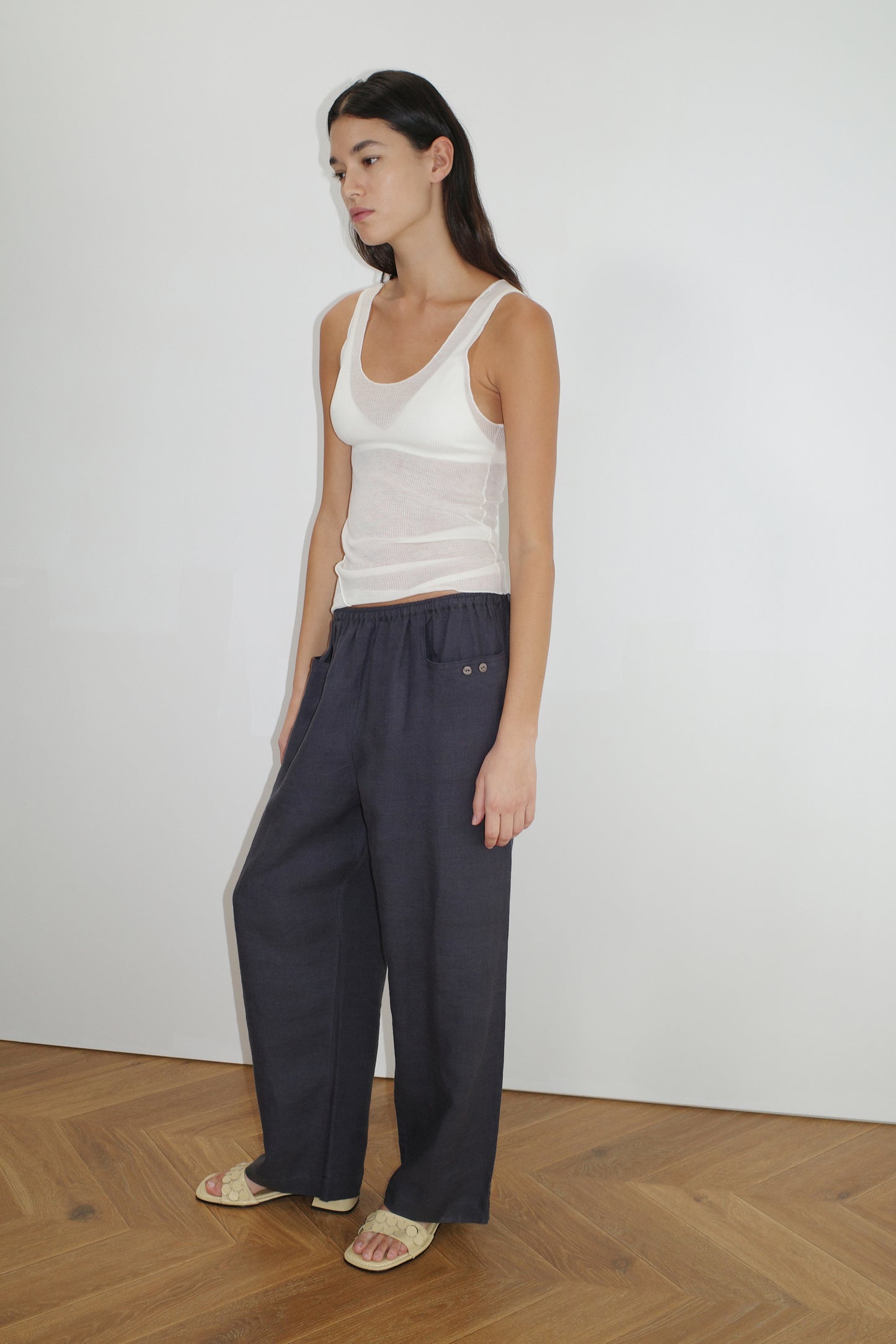 female model wears the linen square pocket pant by Deiji Studios in ink
an ankle length, straight leg pant features a soft minimal elastic waist with front seam pockets and button detail
made from 100% GOTS certified organic, OEKO-TEX 100 certified and EU certified stone washed french linen
paired with a white knit tank