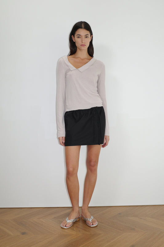 female model wears the cross collar top by Deiji Studios in shell
a sheer fine knit long sleeved top with asymmetric collared neckline, featuring baby locked finishes and a relaxed fit
made from a responsible blend of 85% Recycled Polyester and 15% Viscose
paired with a black cotton skirt