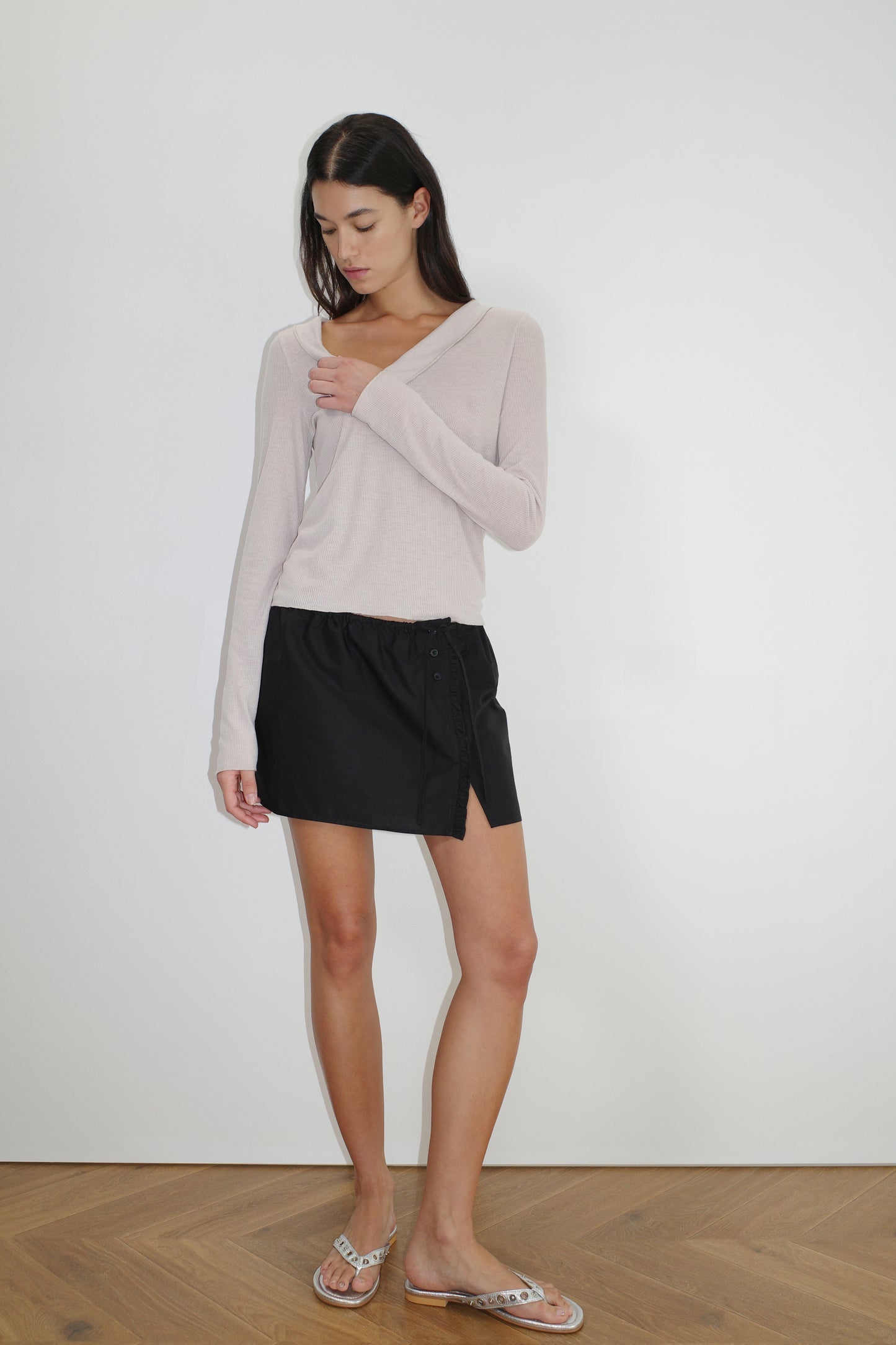 female model wears the ruffle mini skirt by Deiji Studios in black
simple mini skirt designed to sit at low waist features adjustable tie and ruffle edge on side with button detail
made from 100% GOTS certified organic cotton poplin
paired with a sheer knit long sleeve in beige