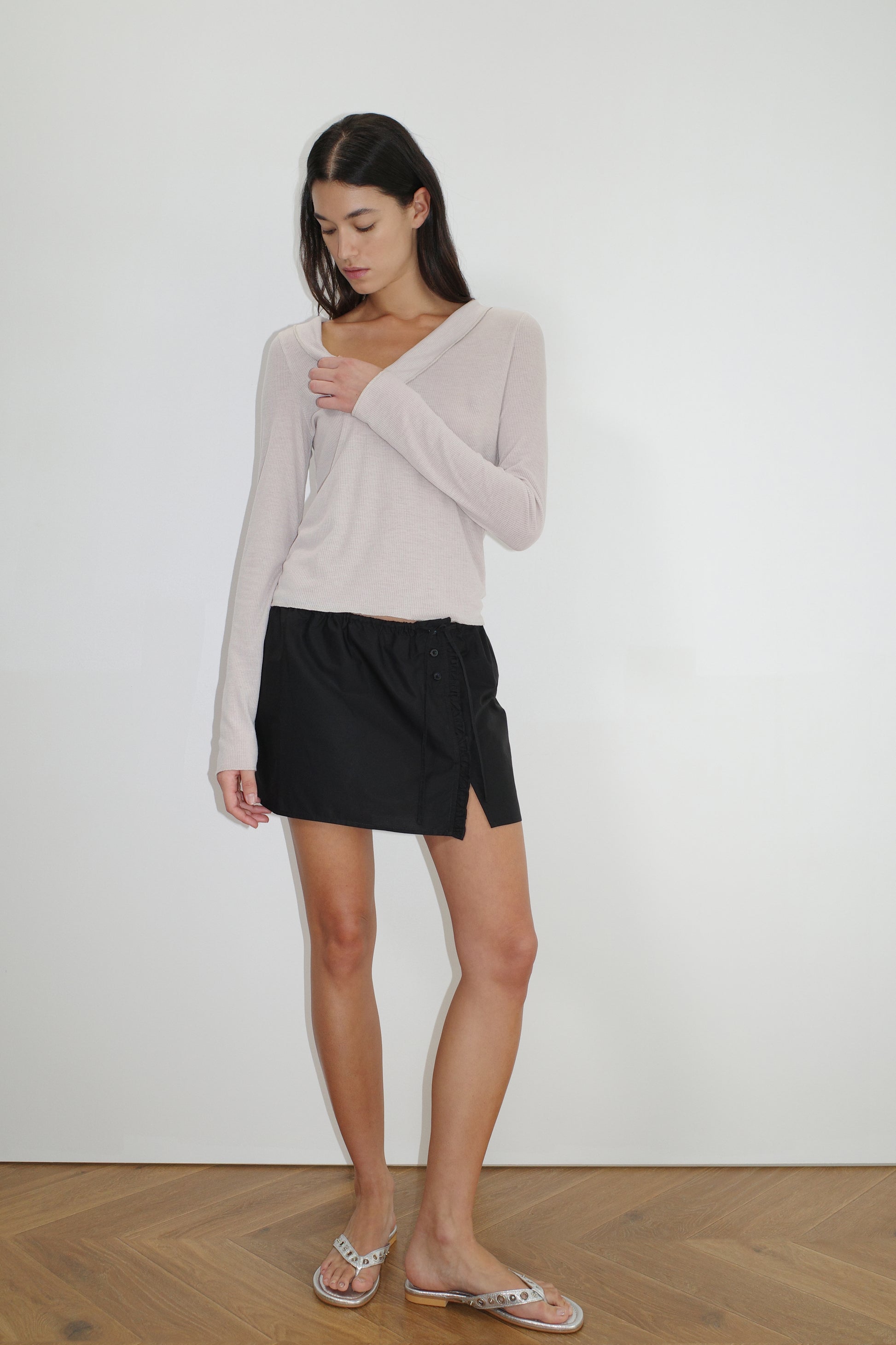 female model wears the ruffle mini skirt by Deiji Studios in black
simple mini skirt designed to sit at low waist features adjustable tie and ruffle edge on side with button detail
made from 100% GOTS certified organic cotton poplin
paired with a sheer knit long sleeve in beige