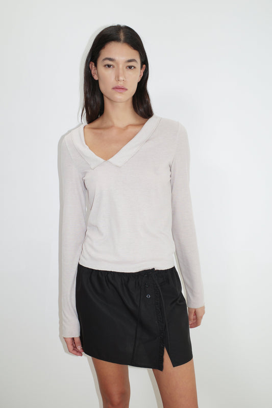 female model wears the cross collar top by Deiji Studios in shell
a sheer fine knit long sleeved top with asymmetric collared neckline, featuring baby locked finishes and a relaxed fit
made from a responsible blend of 85% Recycled Polyester and 15% Viscose
paired with a black cotton skirt