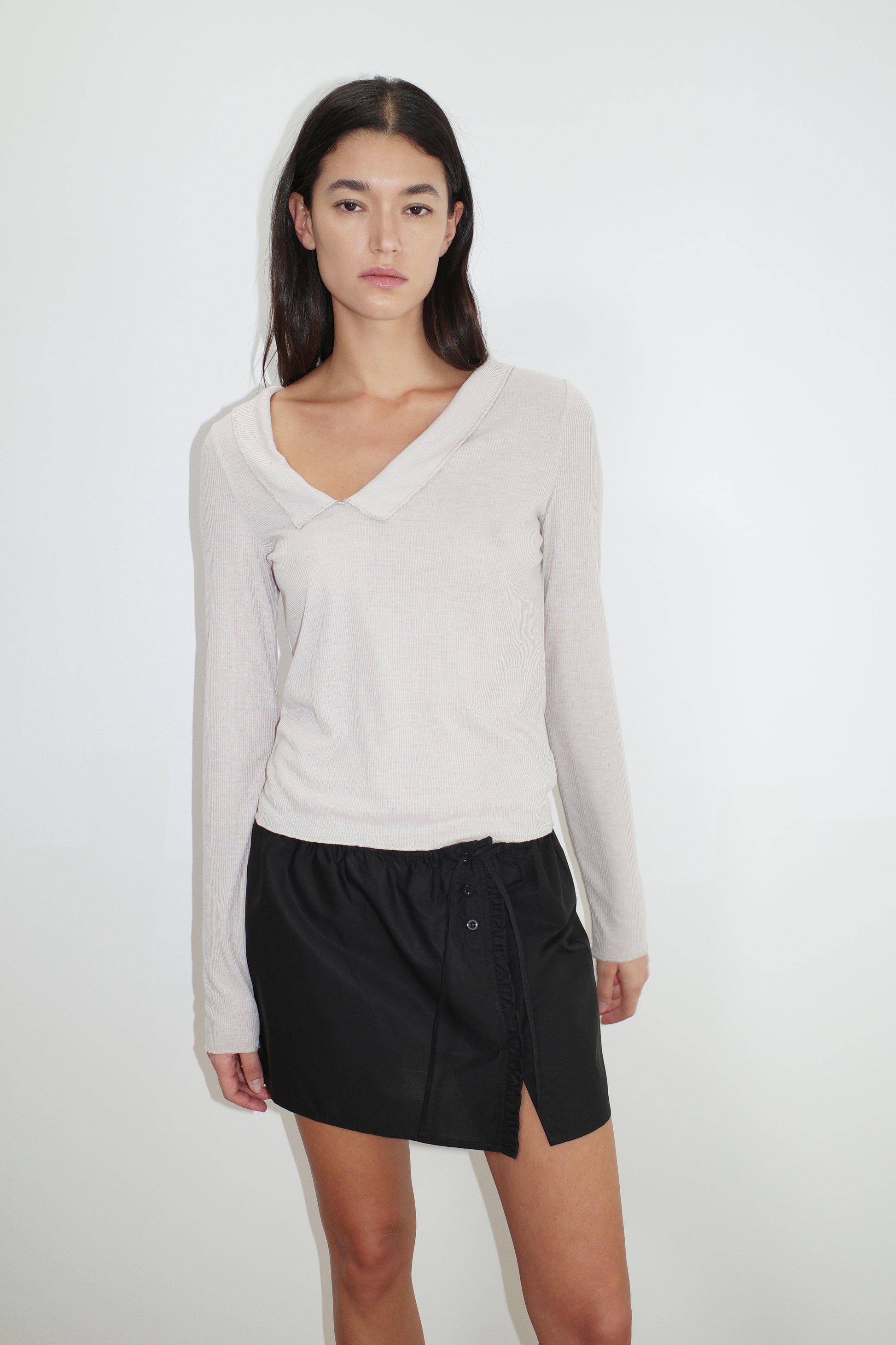 female model wears the ruffle mini skirt by Deiji Studios in black
simple mini skirt designed to sit at low waist features adjustable tie and ruffle edge on side with button detail
made from 100% GOTS certified organic cotton poplin
paired with a sheer knit long sleeve in beige