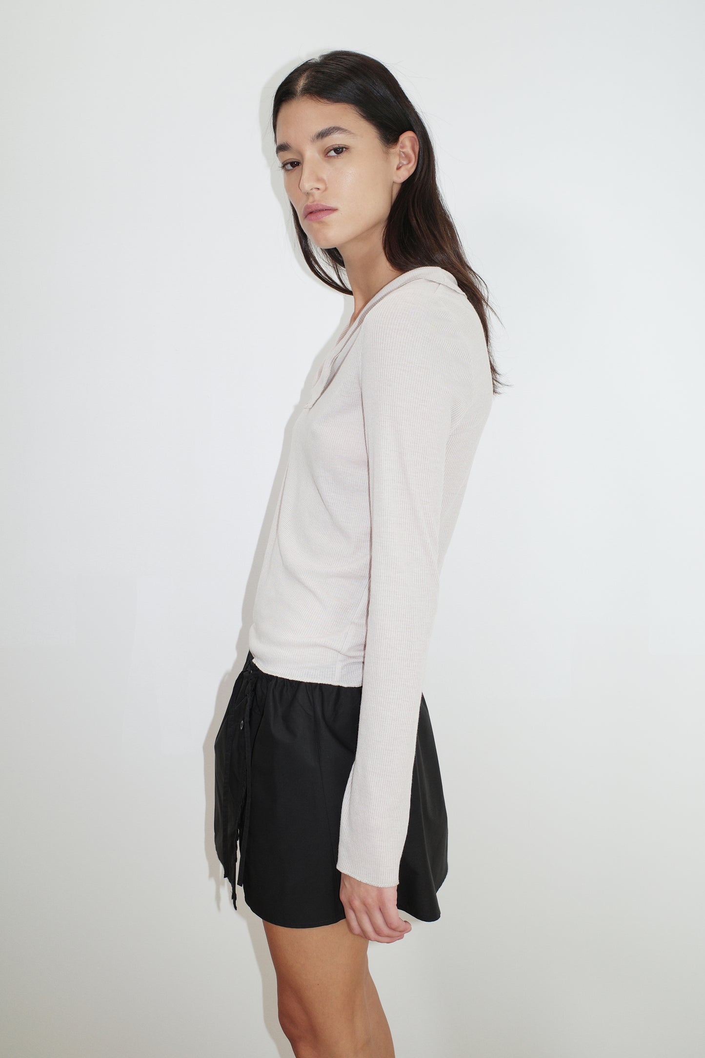 female model wears the ruffle mini skirt by Deiji Studios in black
simple mini skirt designed to sit at low waist features adjustable tie and ruffle edge on side with button detail
made from 100% GOTS certified organic cotton poplin
paired with a sheer knit long sleeve in beige