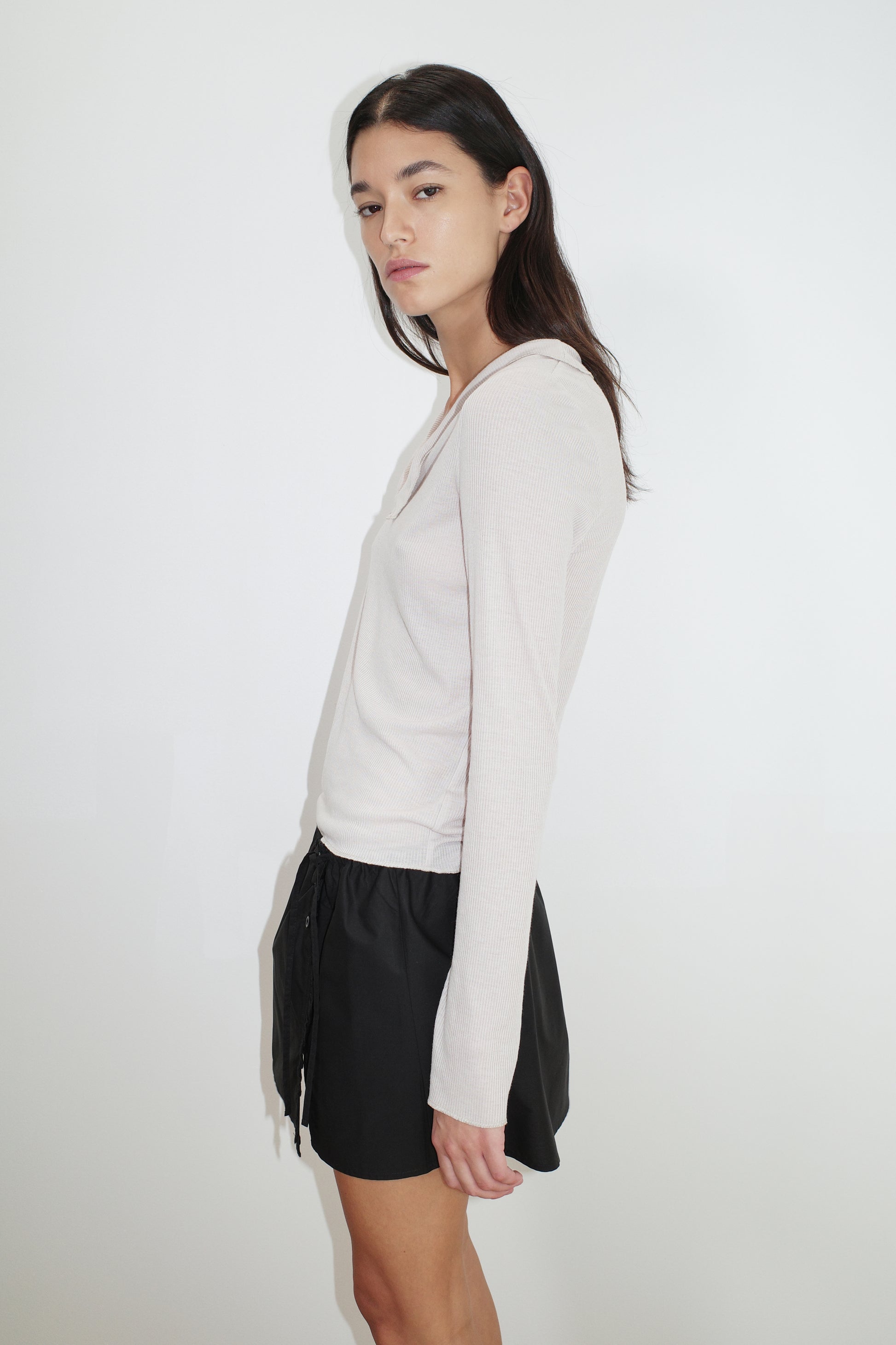female model wears the ruffle mini skirt by Deiji Studios in black
simple mini skirt designed to sit at low waist features adjustable tie and ruffle edge on side with button detail
made from 100% GOTS certified organic cotton poplin
paired with a sheer knit long sleeve in beige