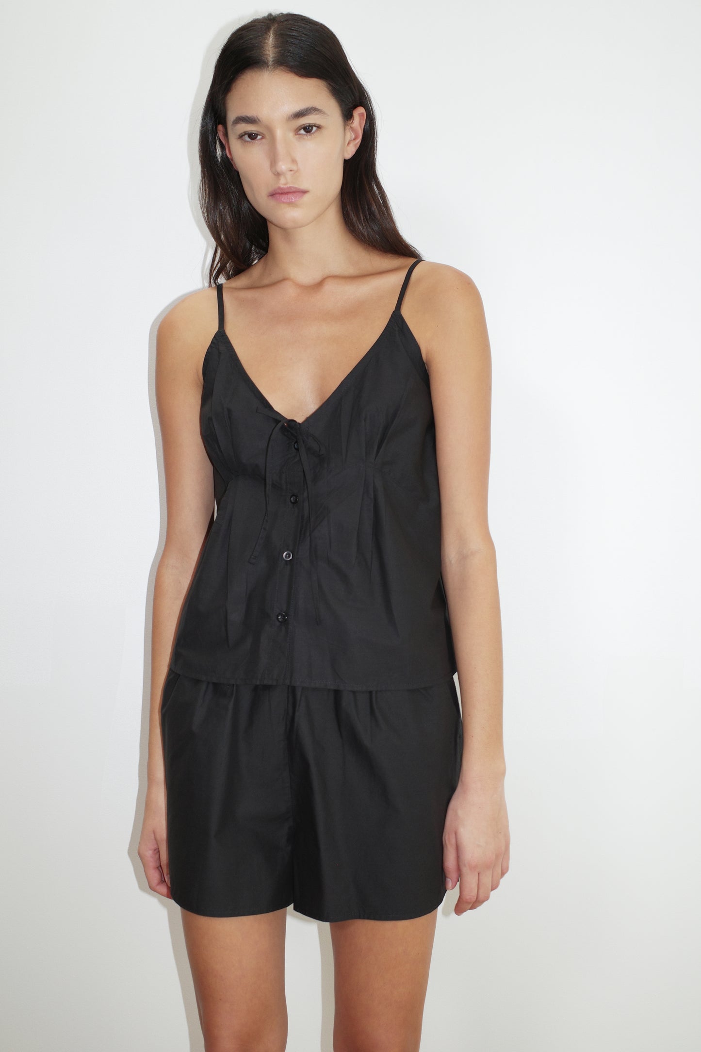 female model wears the placket short set by Deiji Studios in black
a lightweight everyday top features a flattering v neckline, button down front, side fold pleat detail at bust with a self-fabric tie pairs back with an easy pull on short, featuring a soft elastic waist and side seam pockets to wear as a set or separately
made from 100% organic cotton poplin