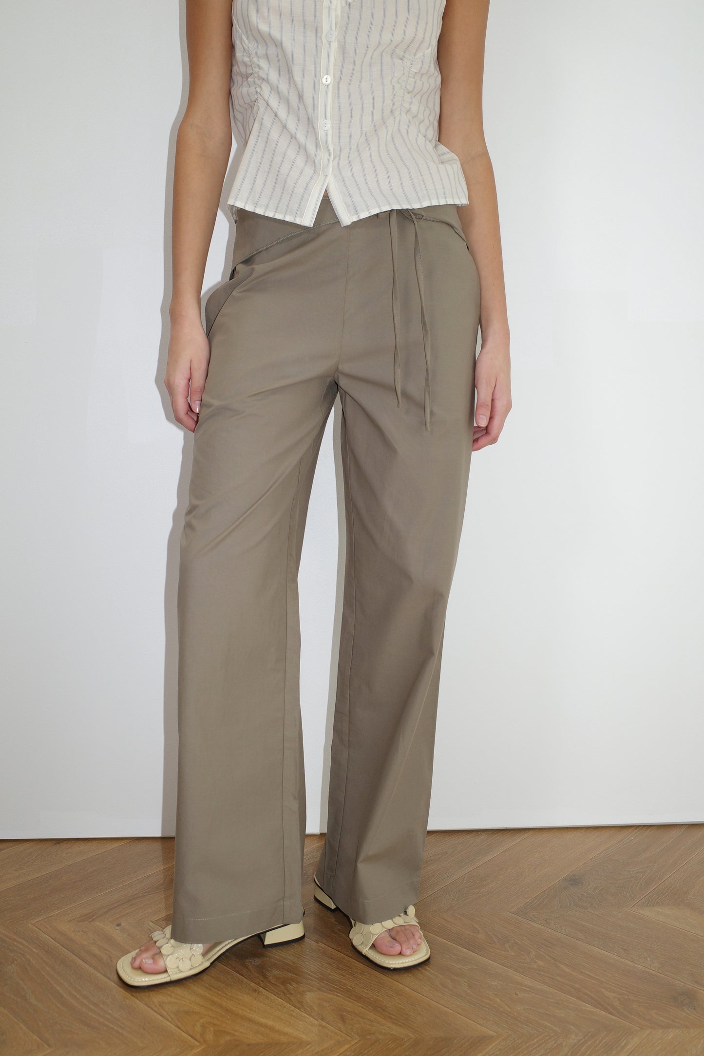female model wears the belted pant by Deiji Studios in clay
mid-rise loose-leg pant with attached tie-front belt detail, babylock hem, and relaxed fit. features concealed zip closure and side pockets
made from 100% organic cotton
paired with a striped singlet top