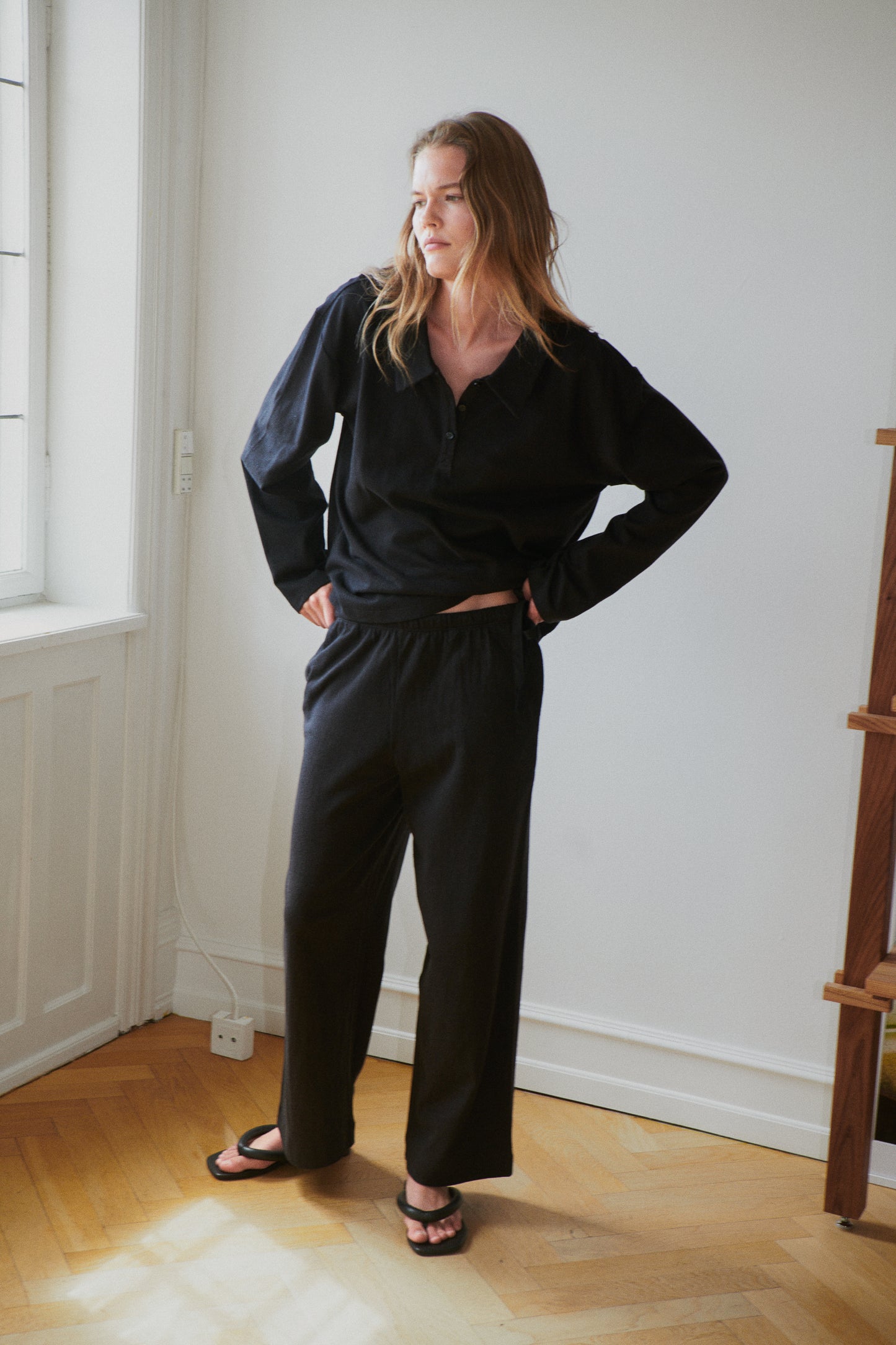 Female model wearing the jersey pant - black by Deiji Studios against plain background