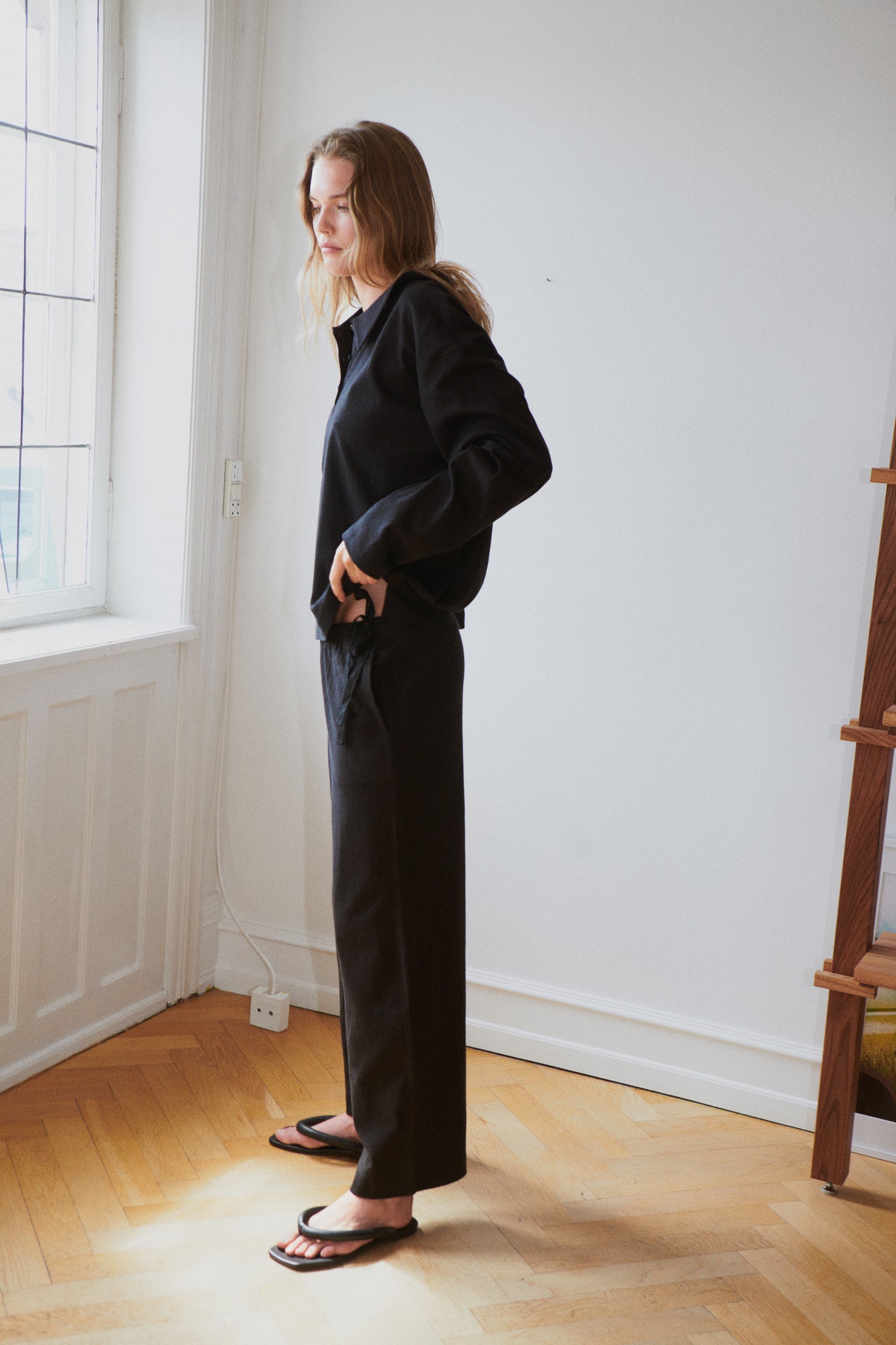 Female model wearing the jersey pant - black by Deiji Studios against plain background
