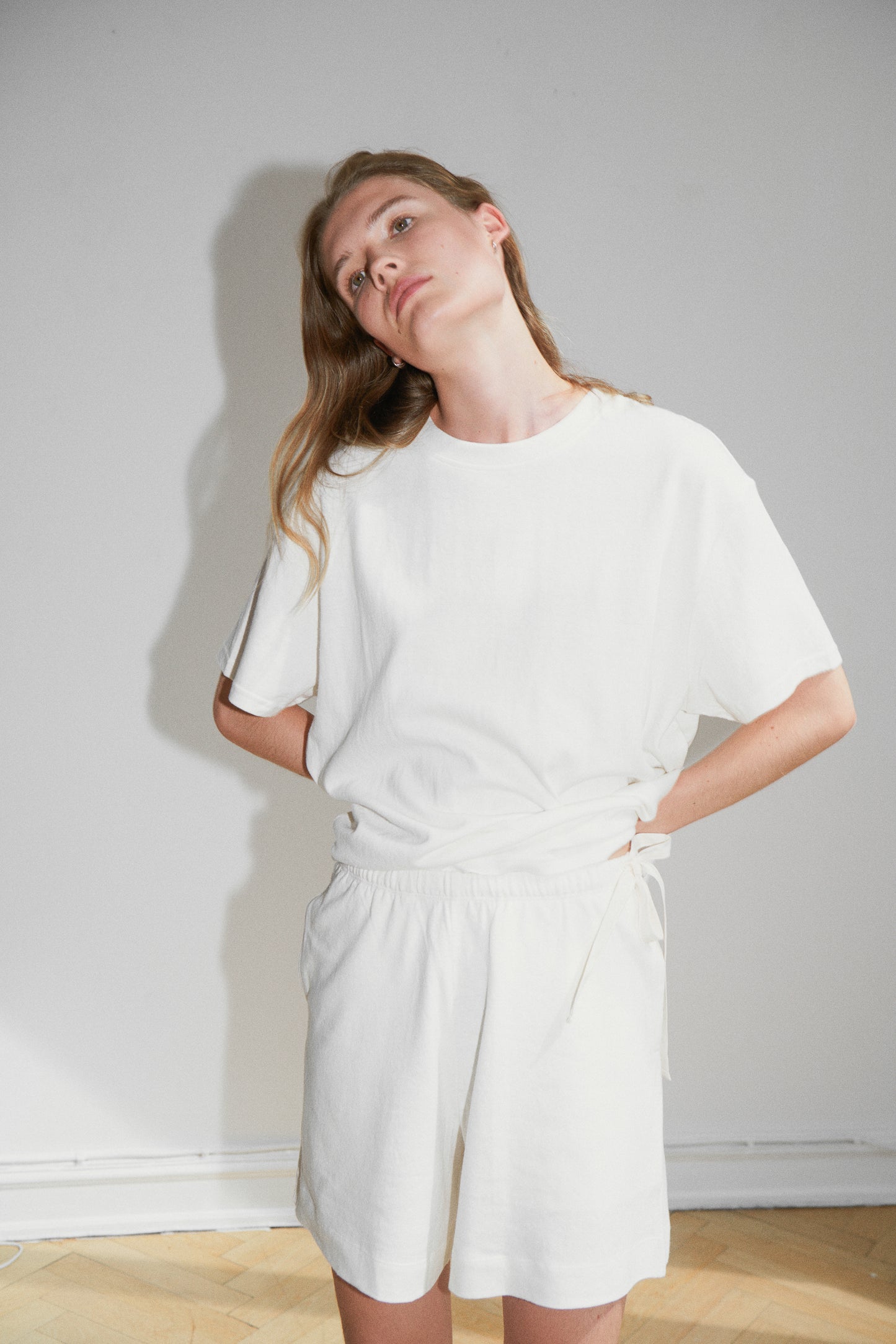 Female model wearing the leisure tee - bone by Deiji Studios against plain background