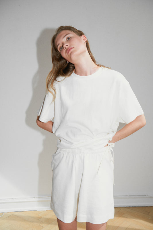 Female model wearing the leisure tee - bone by Deiji Studios against plain background