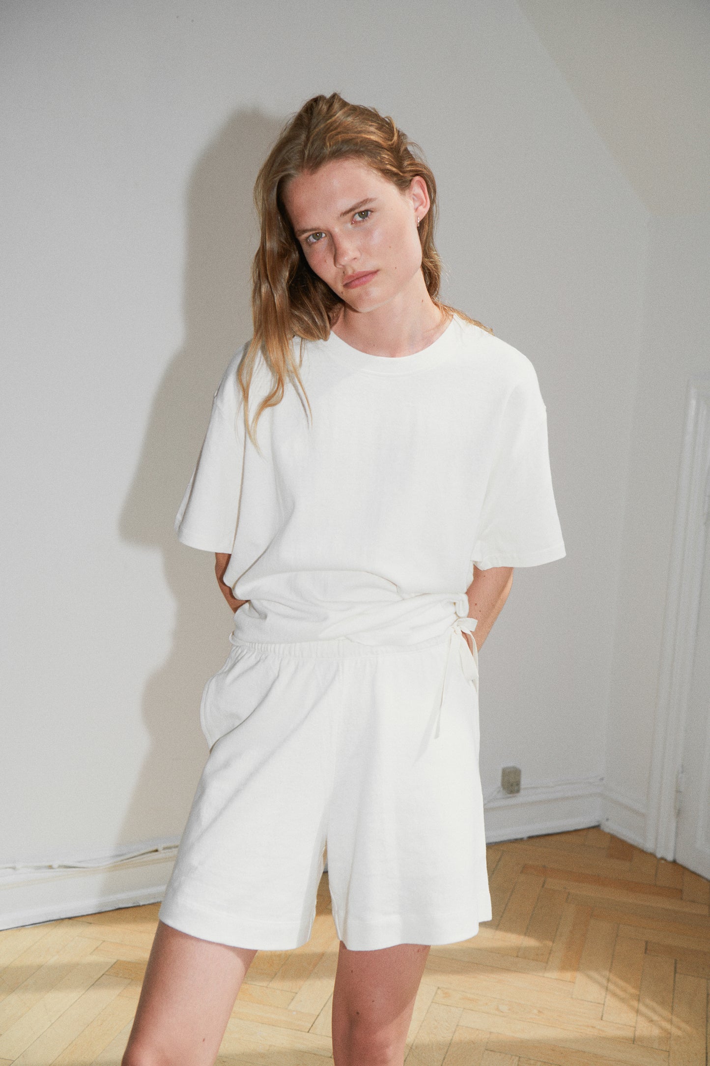 Female model wearing the leisure tee - bone by Deiji Studios against plain background