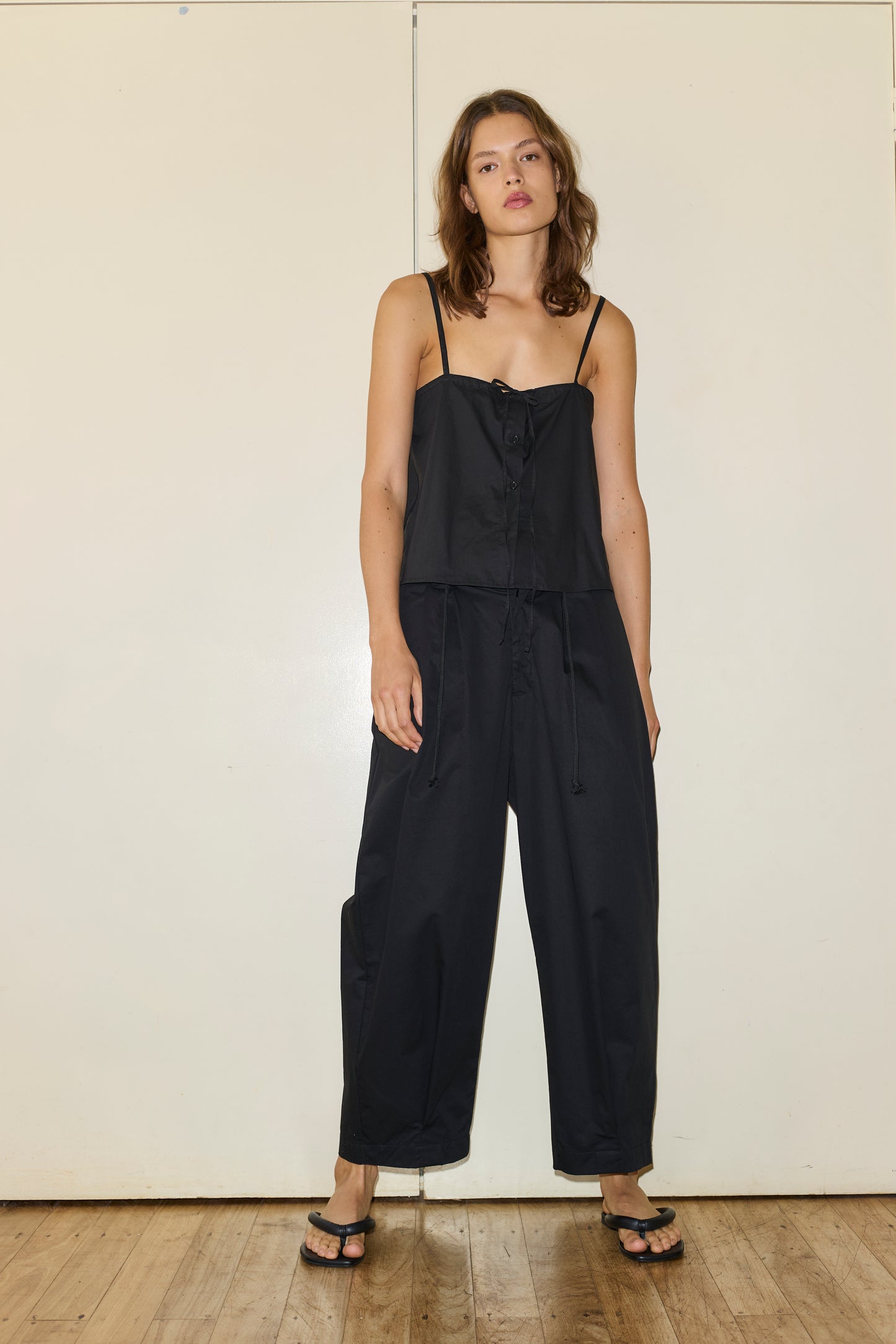 Female model wearing The Placket Strap Top - Black by Deiji Studios against plain background