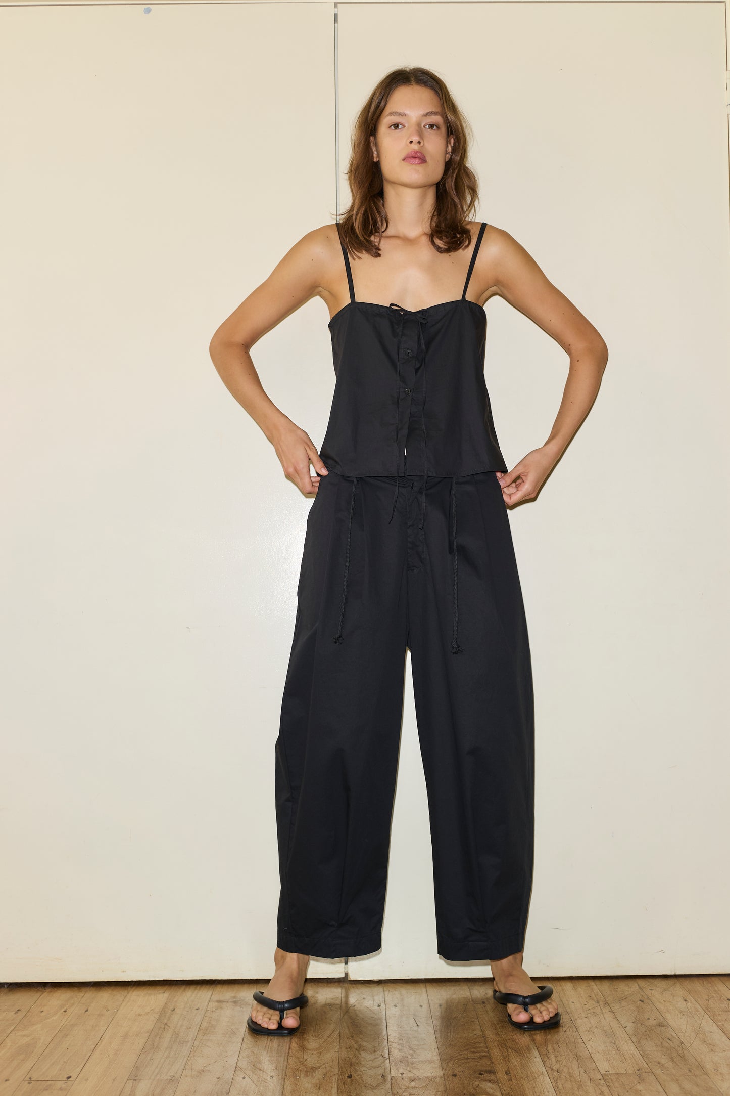 Female model wearing The Placket Strap Top - Black by Deiji Studios against plain background