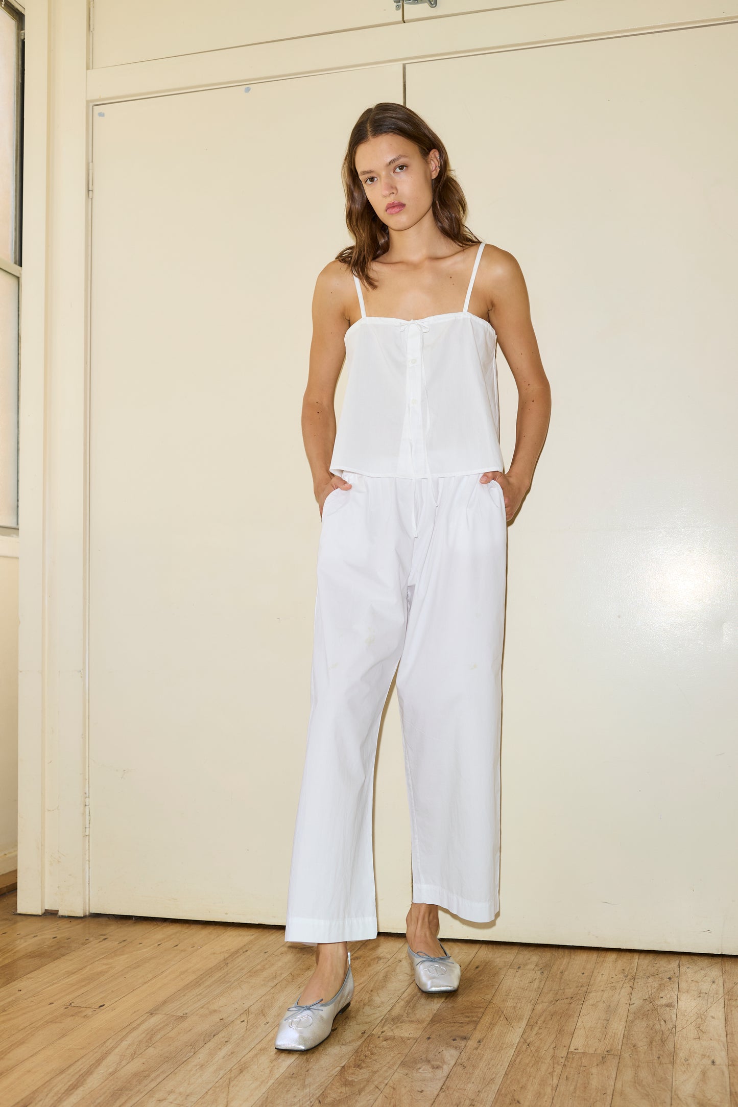 Female model wearing The Placket Strap Top - White by Deiji Studios against plain background