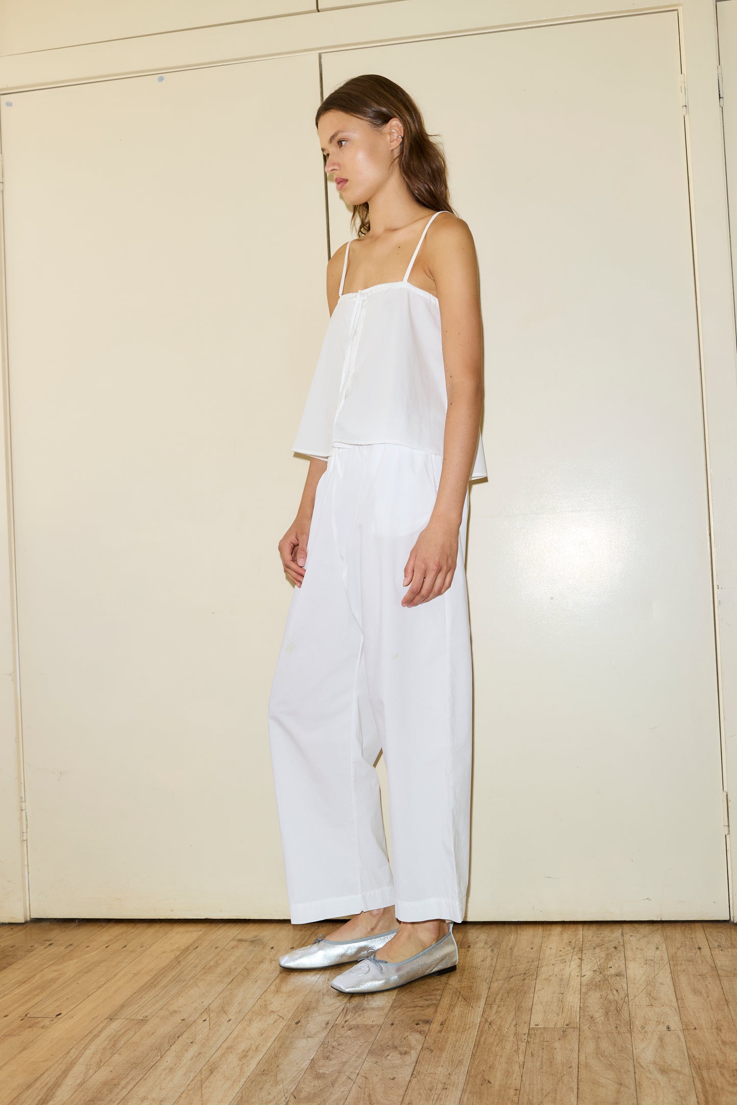 Female model wearing The Placket Strap Top - White by Deiji Studios against plain background