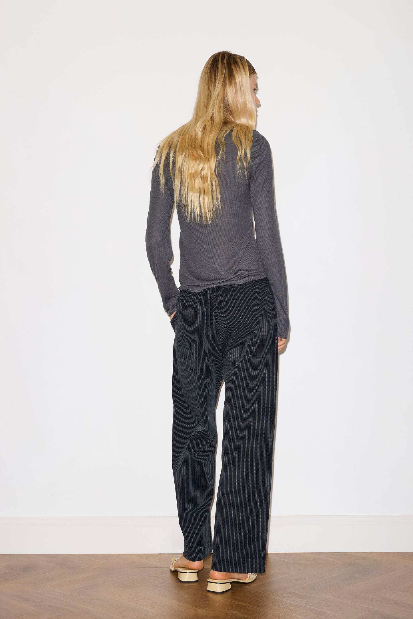 blonde female model wears grey long sleeve top, worn with a navy and yellow striped trouser