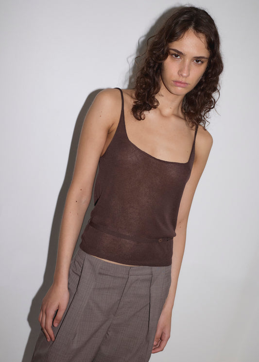 A person with wavy brown hair wears the Square Knit Top - Brown and gray pants, standing against a plain white background and looking slightly downward with a neutral expression.
