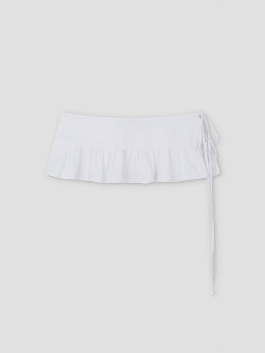 The Flounce Belt is a white mini skirt featuring a ruffled hem and side tie, shown against a plain light gray background.