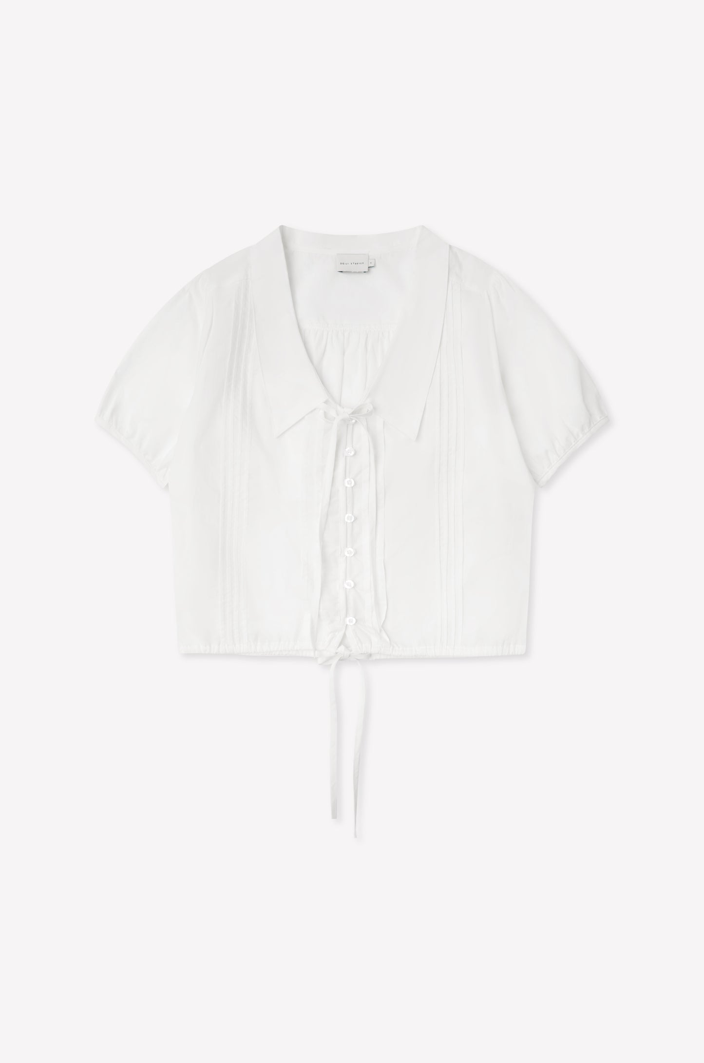 The Fine Collar Top - White features a collared v-neck, short sleeves, button-down front, pintuck details, and a waist tie—crafted from cotton poplin with signature Deiji Studios elegance.
