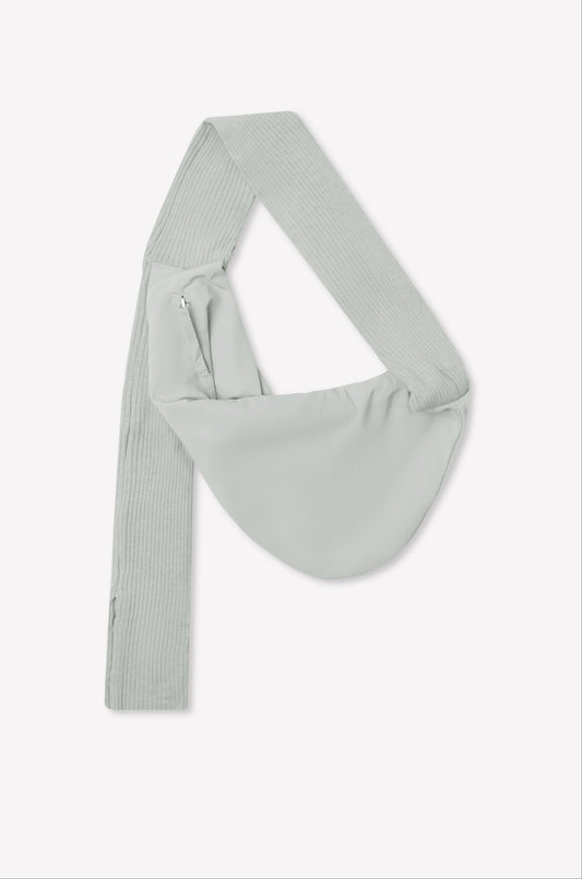 A baby blue asymmetrical sling saddle bag, named Knit Strap Bag, features a wide, ribbed knit shoulder strap and a side zipper, displayed against a plain white background.