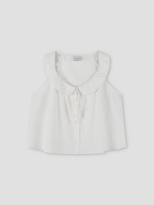 The Round Collar Top - White Texture by Deiji Studios is a sleeveless white top with a wide ruffled collar, front buttons, and a delicate bow tie at the neckline, shown against a plain light background.
