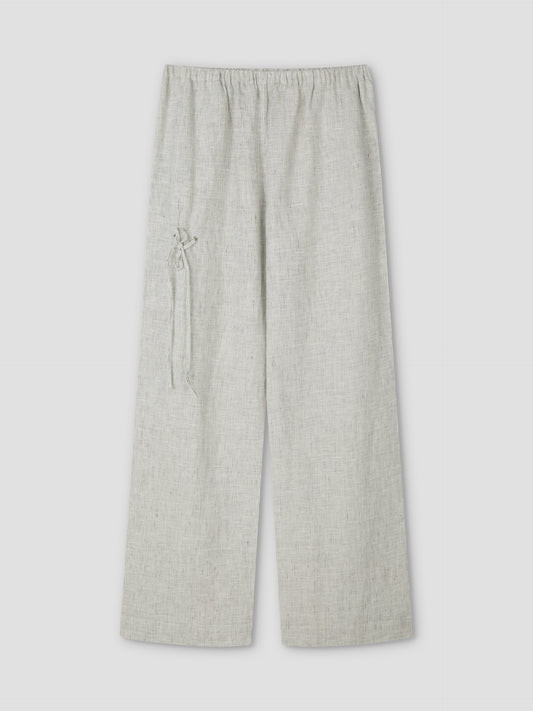 The Eyelet Pant - Fine Stripe by Deiji Studios features a light grey, wide-leg linen design with an elastic waistband, a decorative left-side tie, subtly textured fabric, and relaxed ankle length. Shown flat on a plain background.