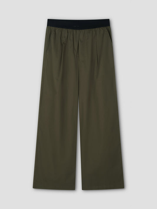 The Contrast Waist Pant - Olive by Deiji Studios features a black elastic waistband, relaxed wide-leg fit, side pockets, and front pleats, shown flat on a light gray background.