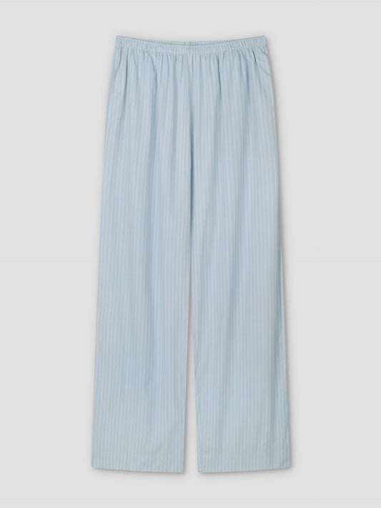 The Ease Trouser - Lake Blue Stripe pajama pants feature light blue and white vertical stripes, a relaxed fit, and an elastic waistband, shown flat on a white background.