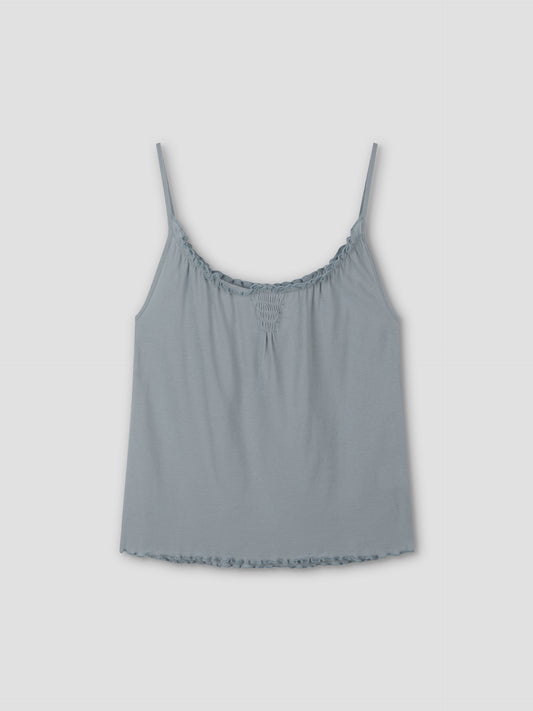 The Cotton Flounce Tank - Baby Blue by Deiji Studios features thin spaghetti straps, gathered neckline, and ruffled hem, shown against a plain light gray background.
