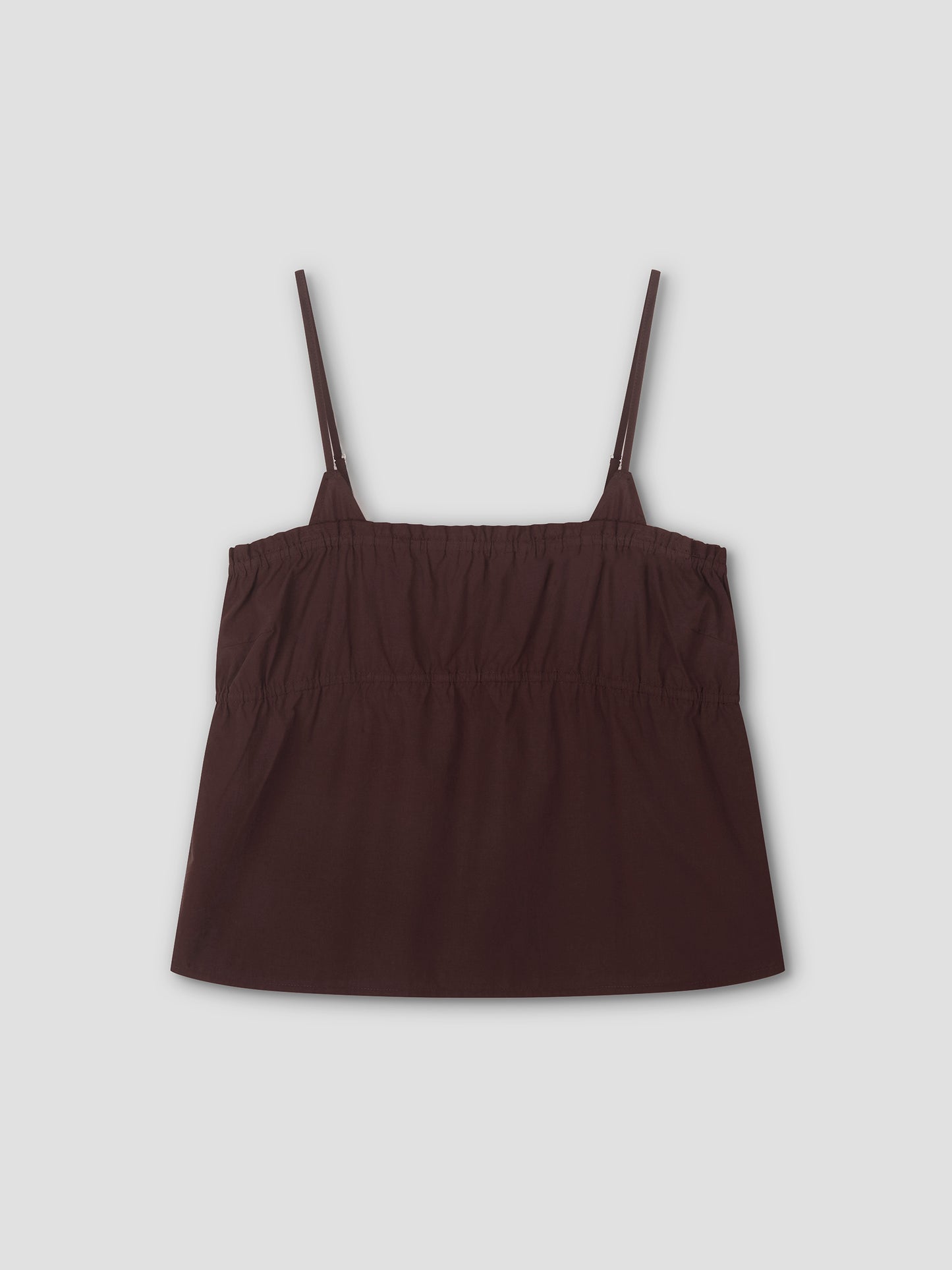 The Tri Cami - Sepia is a dark brown, sleeveless cami top with thin adjustable straps and an elasticized gathered chest, offering a relaxed silhouette. Shown laid flat on a light gray background.