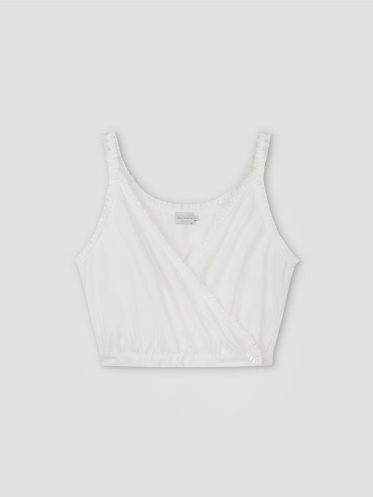 The Overlie Top - White features thin shoulder straps, a sleeveless wrap-style front, and gathered elastic at the hem, shown against a plain light gray background.