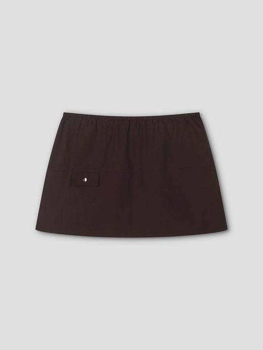 The Pocket Skirt - Sepia features an elastic waistband and a small buttoned flap pocket on the left, true to Deiji Studios style. This chic black mini skirt is displayed against a plain light gray background, perfect for any occasion.