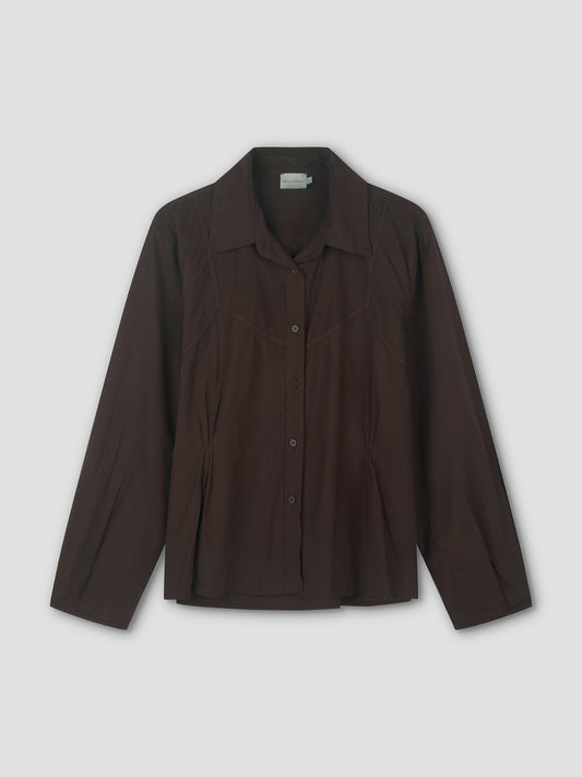 The Cami Overshirt - Sepia is a long-sleeved, dark brown button-up shirt with a pointed collar and subtle seam details, perfect for relaxed layering or wearing over a cami, shown on a plain light background.