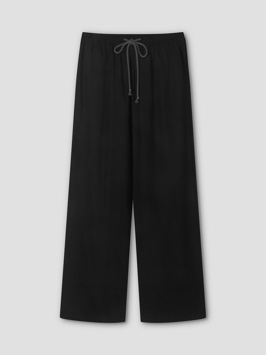 The Layered Pant - Black by Deiji Studios is a black wide-leg relaxed pant featuring an elastic waistband and visible drawstring, shown flat against a light gray background—a minimalist wardrobe staple.