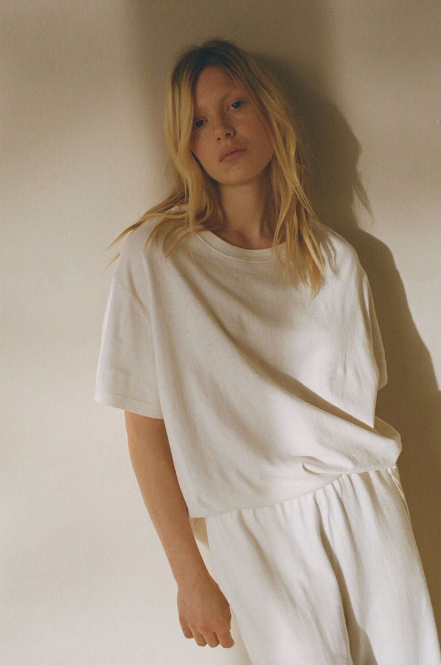 Female model wearing the leisure tee - bone by Deiji Studios against plain background