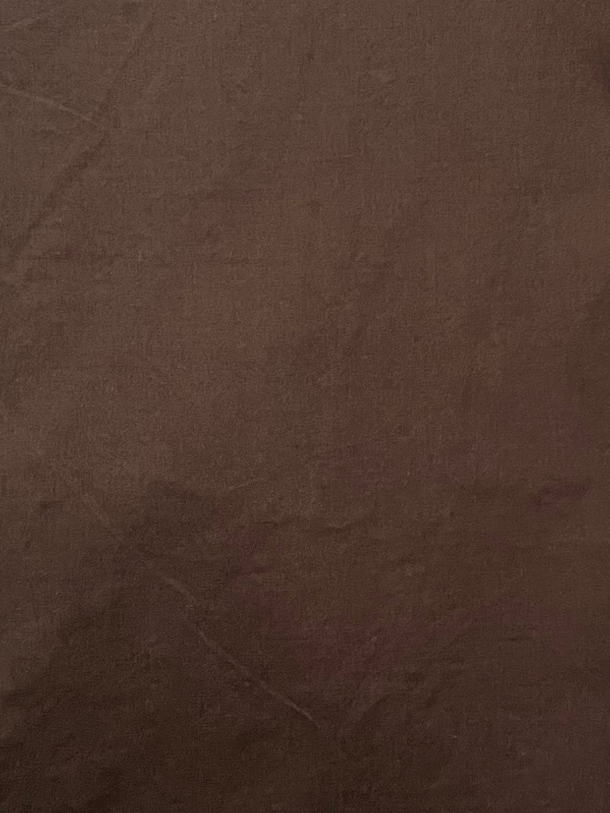 A close-up of chocolate brown fabric, revealing subtle creases and textured detail—evoking the relaxed feel of the Ease Trouser - Chocolate by Deiji Studios.