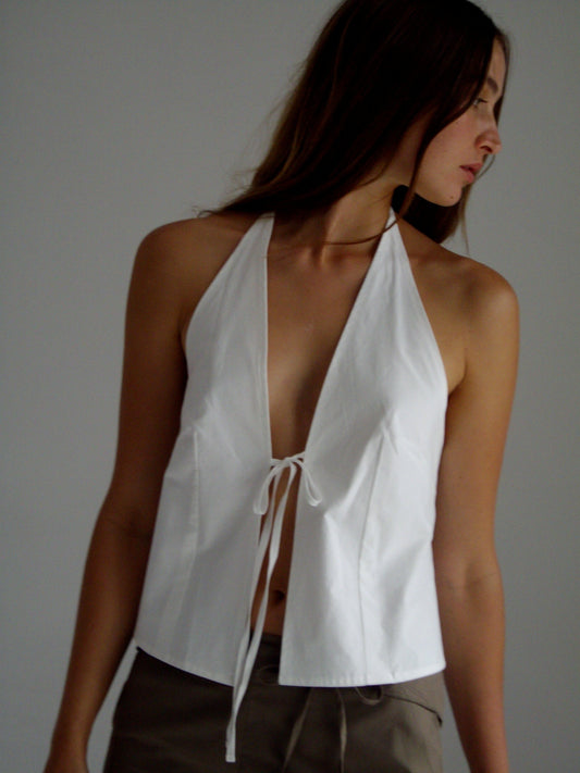 female model wears the open halter top top by Deiji Studios in white
top features open front with centre bust tie, halter neck tie and v neckline, bust seams for subtle shaping and shirred back
made from 100% GOTS certified organic cotton poplin
paired with a cay green cotton trouser