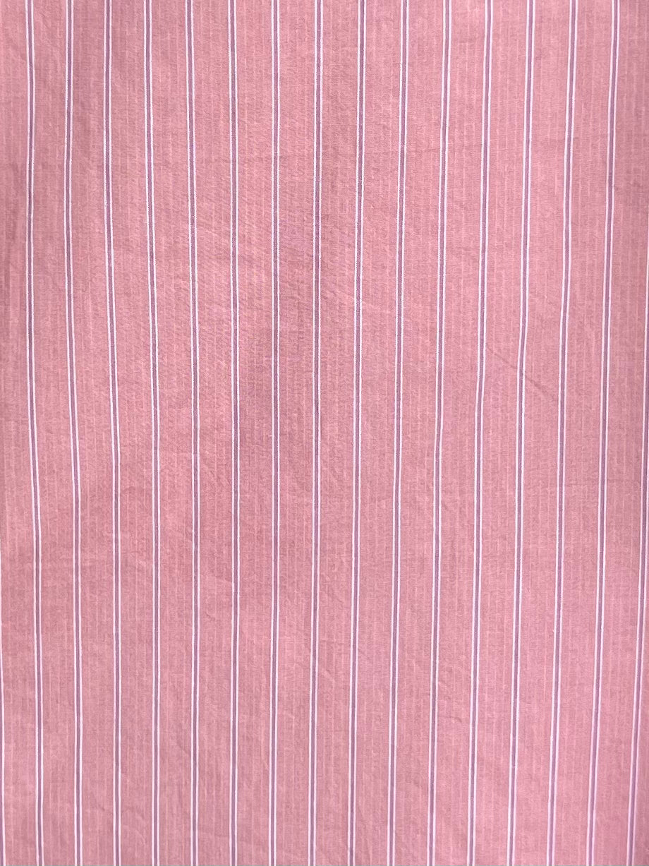 Close-up of the Arch Tie Shirt - Salt Stripe by 0, made from pink organic cotton poplin featuring thin, evenly spaced vertical white stripes and a soft texture—ideal for its boxy fit design.