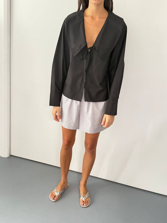 the collared tie shirt by Deiji Studios in black
a structured shirt features an oversized collar and cuff, tie at front collar opening, dropped shoulder and elongated sleeves in a boxy fit
made from 100% GOTS certified organic cotton poplin
paired with a blue stripe cotton boxer
