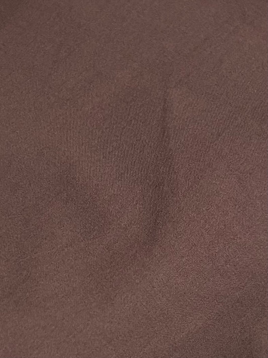 A close-up of the Button Skirt - Chocolate shows brown organic cotton fabric with subtle creases and shadows, creating an uneven texture that reflects Deiji Studios signature relaxed style.