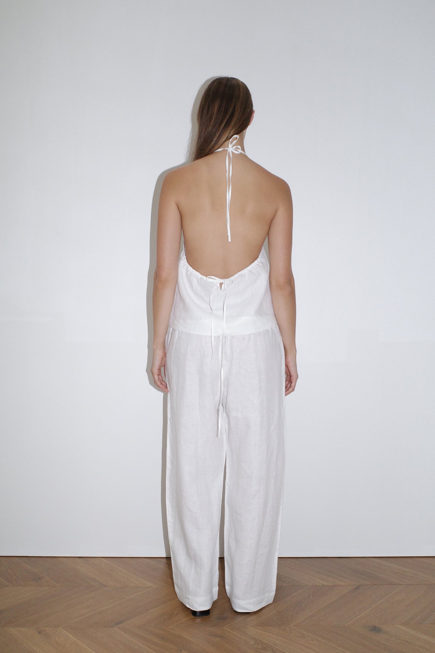 female model wears the linen square pocket pant by Deiji Studios in white
an ankle length, straight leg pant features a soft minimal elastic waist with front seam pockets and button detail
made from 100% GOTS certified organic, OEKO-TEX 100 certified and EU certified stone washed french linen
paired with a white linen halter top