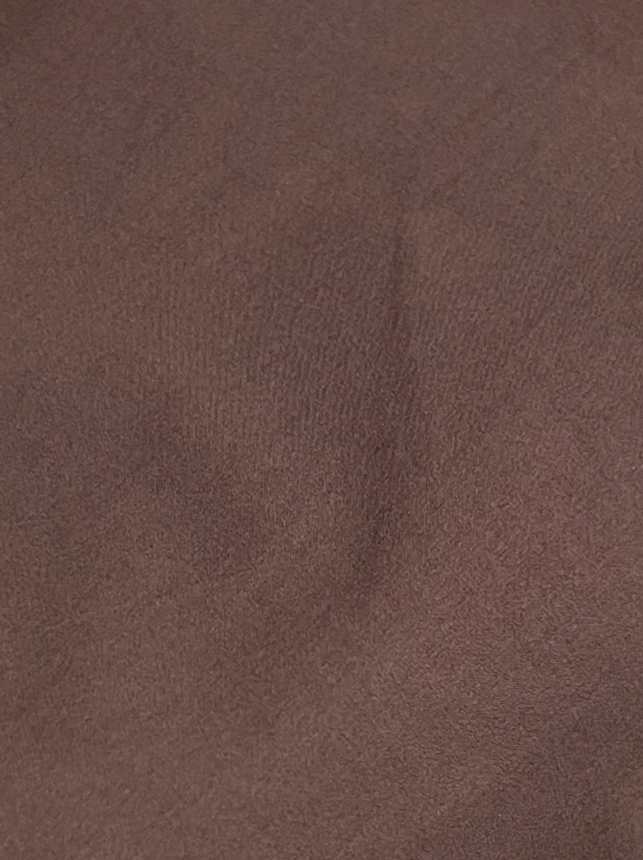A close-up of the brown, textured organic cotton fabric with gentle folds and shadows highlights the soft, lightly uneven surface—ideal for the Napkin Belt - Chocolate by Deiji Studios.